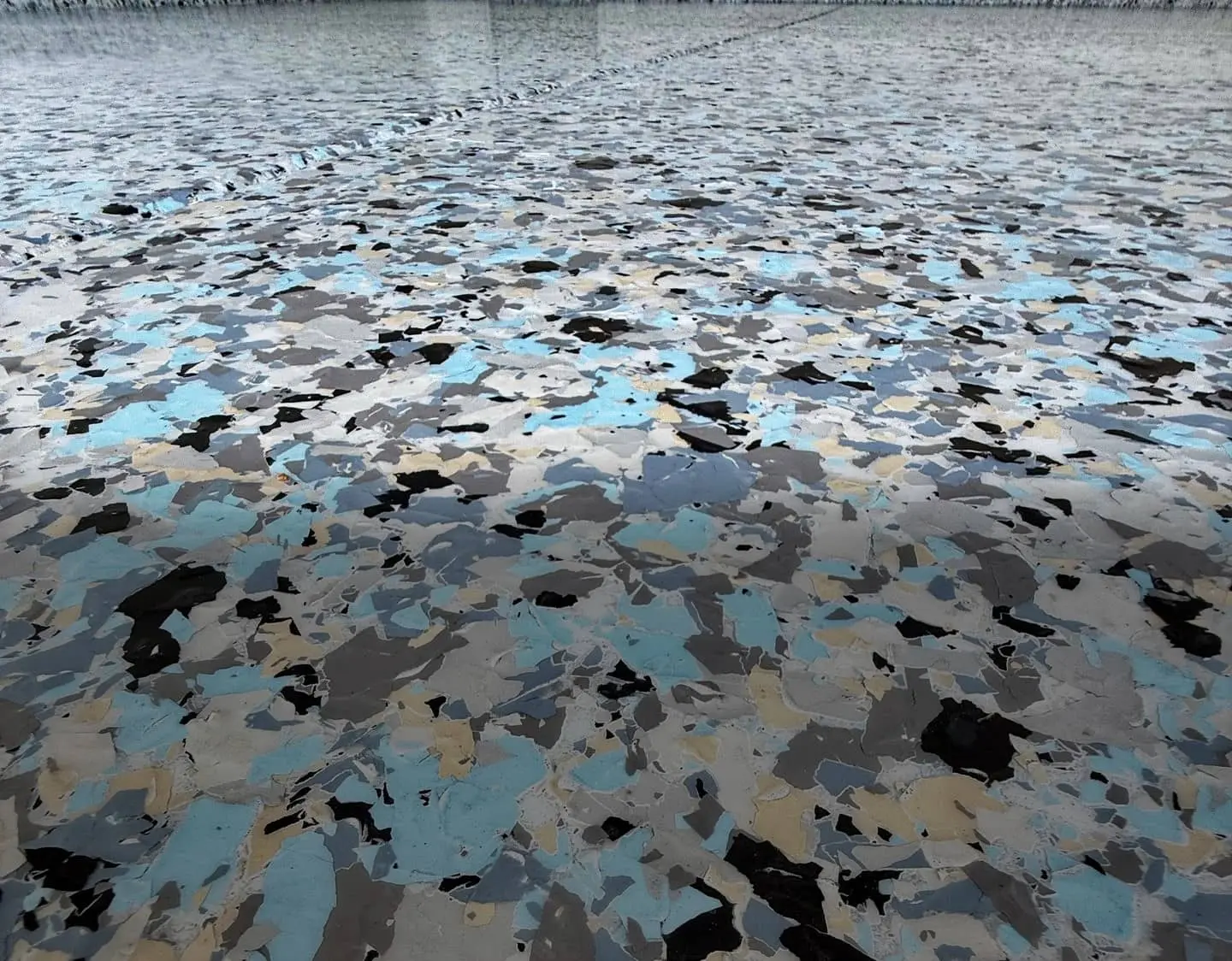 A finished garage floor in blue, gray, black and tan one-inch flake, still glossy under the top coat